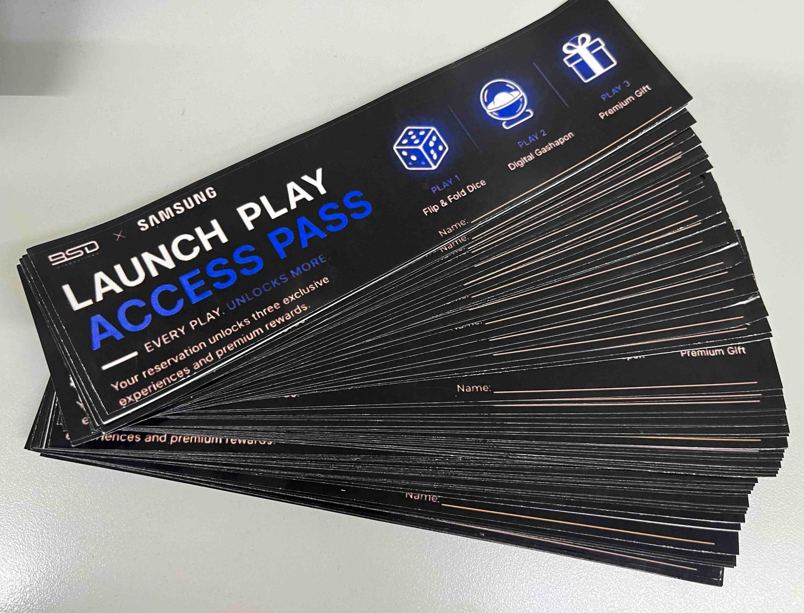Fanned stack of BSD x Samsung Launch Play Access Pass cards, showing Play 1 Flip and Fold Dice, Play 2 Digital Gashapon, and Play 3 Premium Gift